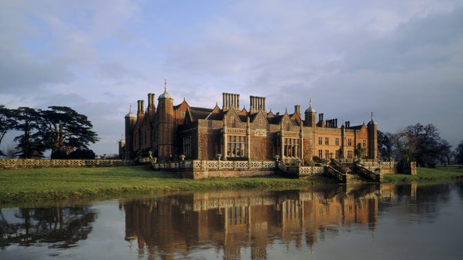 Autumnal view of the house at Charlecote Park from across a lake